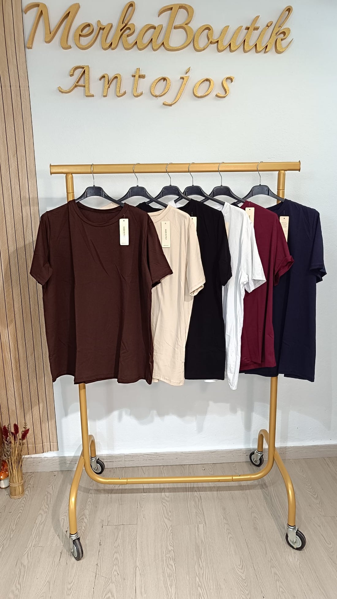 Camiseta básica de algodón de manga corta curvy en chocolate, beige, negro, blanco, burdeos y azul marino, expuesta en perchero