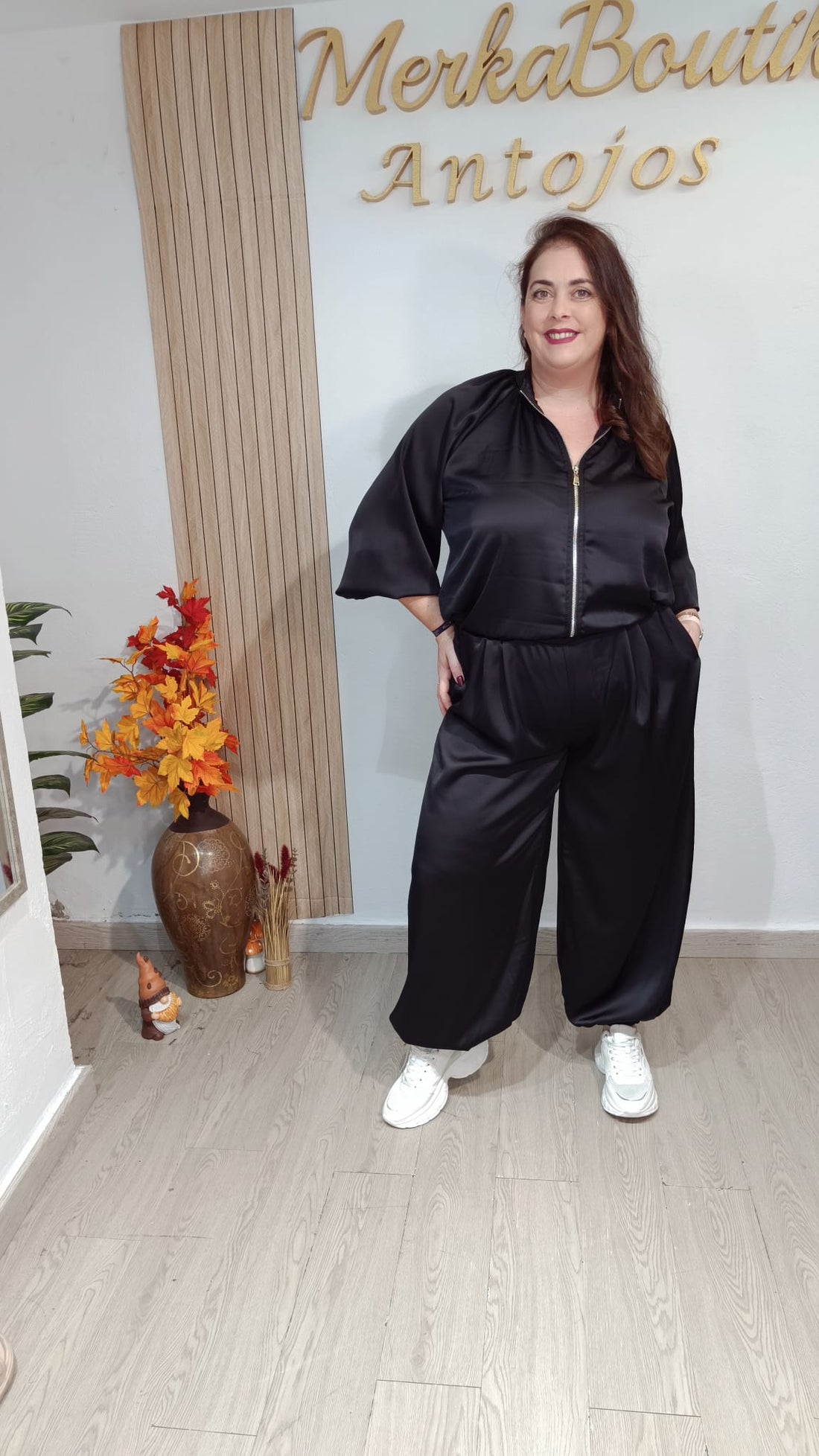 Conjunto Bombacho Satinado Mini negro, con chaqueta de cremallera y pantalón bombacho, llevado por modelo.