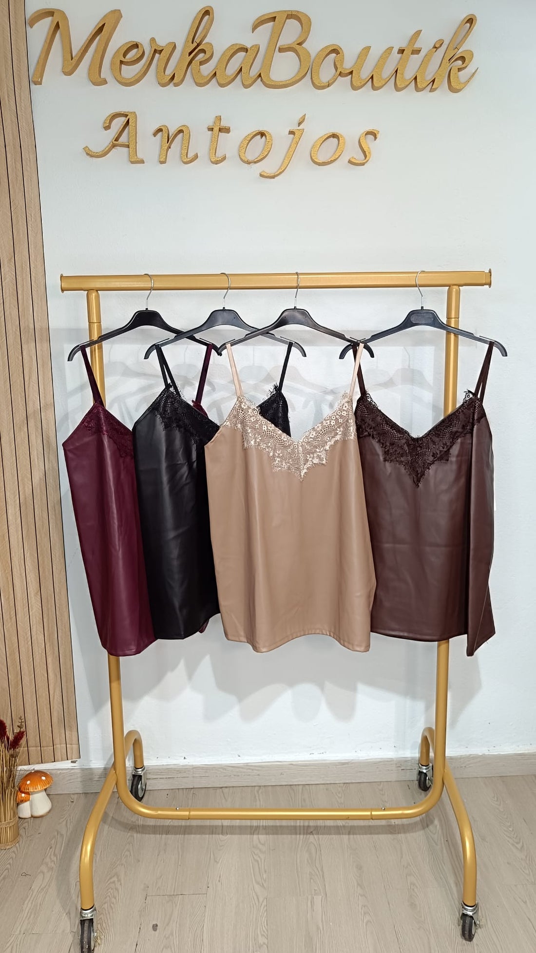 Tops lenceros de polipiel con encaje floral en burdeos, negro, beige y chocolate, colgados en perchero